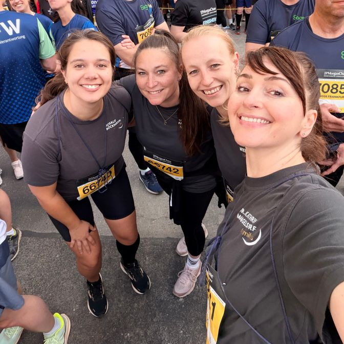 Vier Kolleginnen im Praxis-Shirt mit Startnummern beim Firmenlauf in Frankfurt